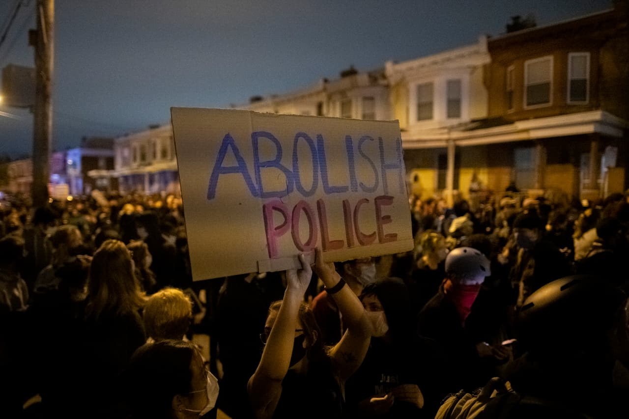 Un manifestante sostiene un cartel que dice "ABOLIR LA POLICÍA" durante una protesta cerca del lugar donde Walter Wallace, Jr. fue asesinado por dos policías.