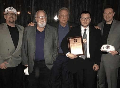 Campos con un grupo de colegas, su placa de reconocimiento y un bastón.
