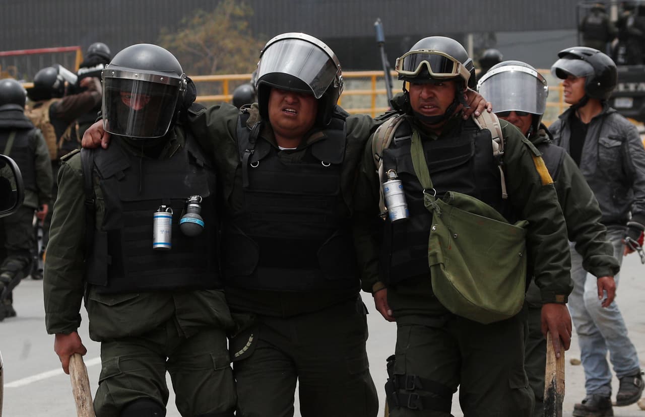 Agentes policiales auxilian a uno de sus compañeros herido en enfrentamientos con manifestantes pro Morales. Los grupos violentos han bajado desde la ciudad de El Alto, vecina de La Paz y reducto de Morales donde una tuba quemó comercios y atacó recintos policiales desde la víspera.