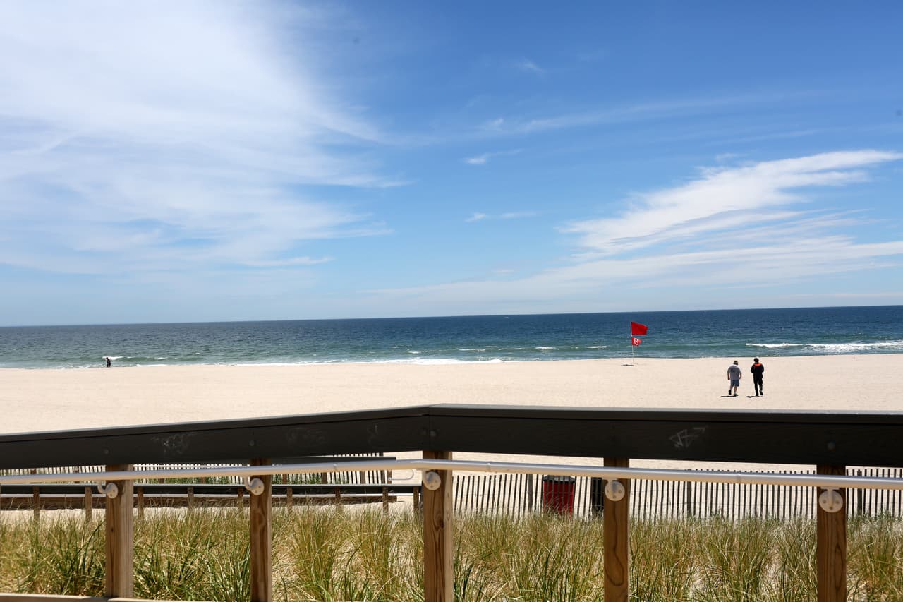 Dos persona caminan por una playa vacía en Nueva Jersey.