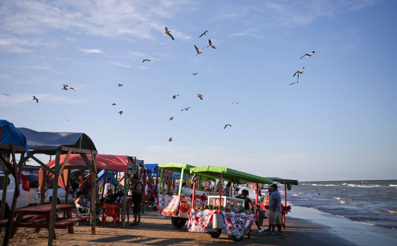 Las gaviotas sobrevuelan los puestos de comida en Playa Bagdad. Unas pocas millas al norte desemboca el Río Bravo (o río Grande para los estadounidenses), el serpenteante límite natural que divide México de EEUU en una extensión de 1,885 millas. 
<a href="https://www.univision.com/noticias/inmigracion/en-estos-lugares-la-naturaleza-interrumpe-al-muro-fronterizo-fotos-fotos">A diferencia de la frontera en la costa del océano Pacífico</a>, aquí no hay barras de hierro que se meten en el mar para evitar el cruce de indocumentados. Los miles de migrantes que cruzan México para buscar asilo en EEUU y se acumulan en otros puntos al oeste no se acercan a esta playa.