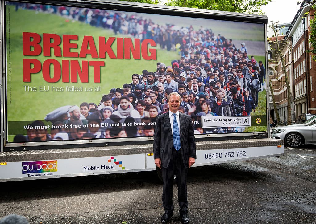 Nigel Farage posa delante de un cartel de apoyo al Brexit que muestra refugiados sirios junto al lema "Punto de Quiebre"