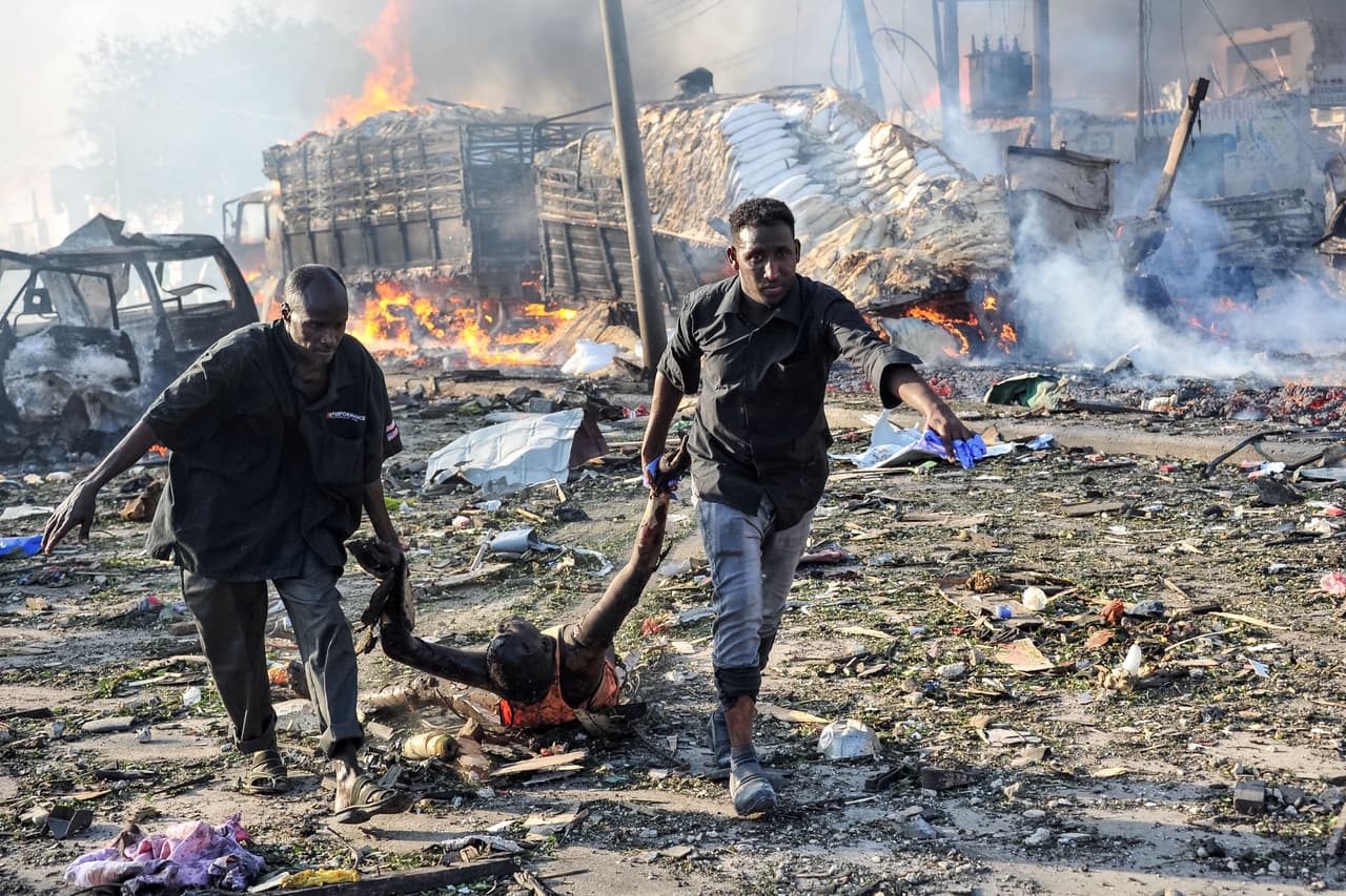 Dos hombres llevan el cuerpo de una víctima después de la explosión de una bomba de camión en el centro de Mogadiscio.