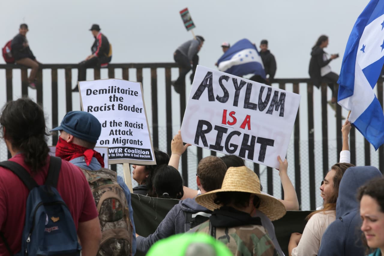 "El asilo en un derecho¨se lee en el cartel de una manifestante del lado estadounidense. A comienzos de abril, la caravana llegó a reunir hasta 1,500 migrantes provenientes de Honduras, Guatemala y El Salvador, desatando la ira del presidente Donald Trump, quien ordenó a sus funcionarios de inmigración endurecer las medidas para detener la entrada ilegal de sus integrantes.