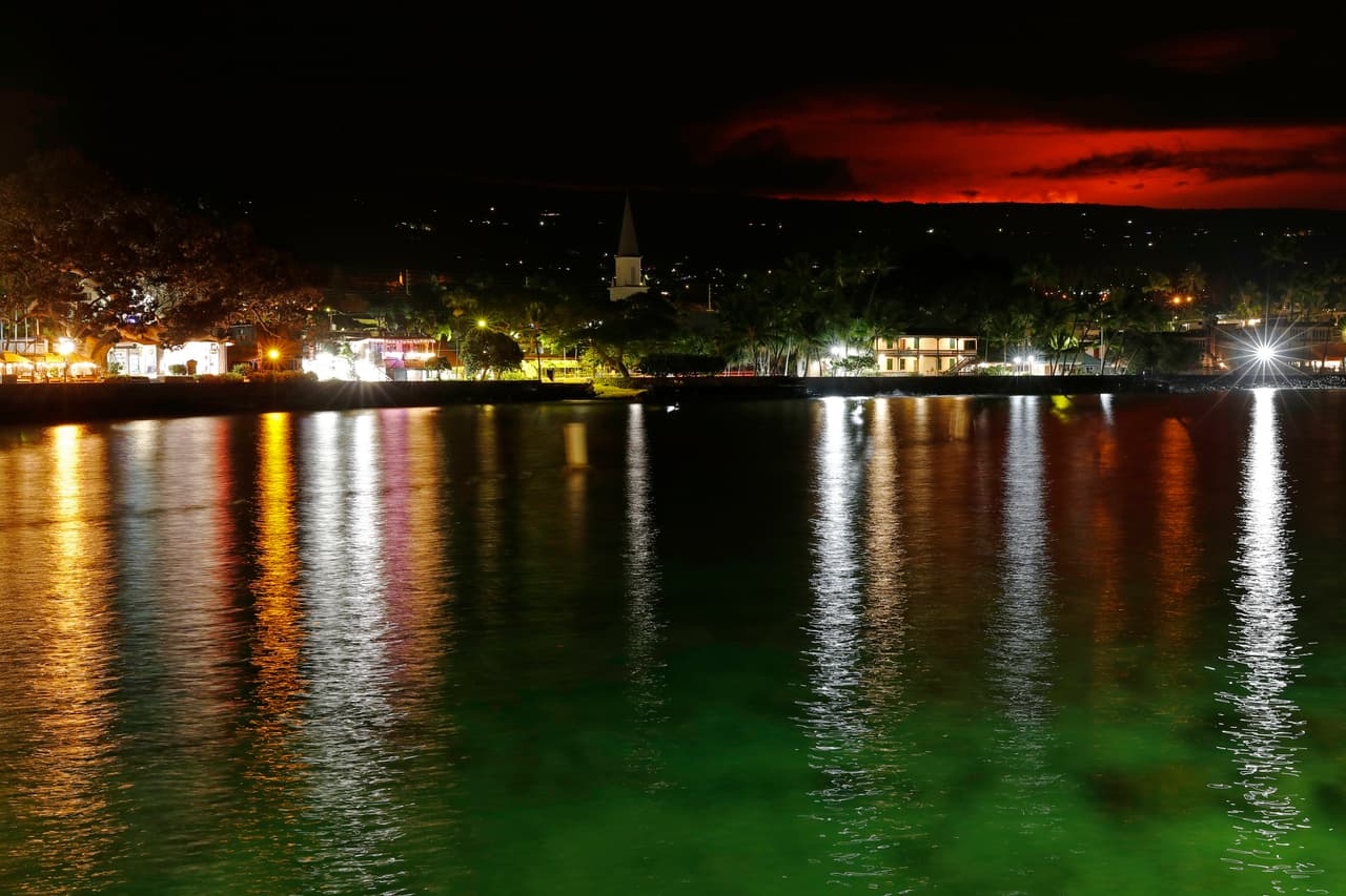 El brillo provocado por el fuego y explosiones de la erupción del volcán Mauna Loa se observa desde la bahía de Kona, Hawaii. Funcionarios dijeron a los residentes que estén listos para evacuar si los flujos de lava empiezan a dirigirse hacia zonas pobladas.