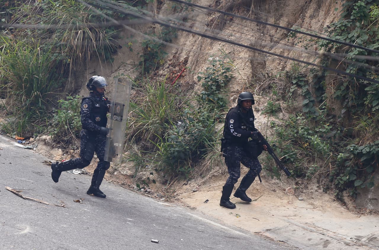 Un par de funcionarios de la Policía Nacional Bolivariana intentan dispersar a los manifestantes que se congregaron en los alrededores de la sede militar minutos después de la declaración por redes sociales de un grupo de guardias nacionales en contra del gobierno de Nicolás Maduro.