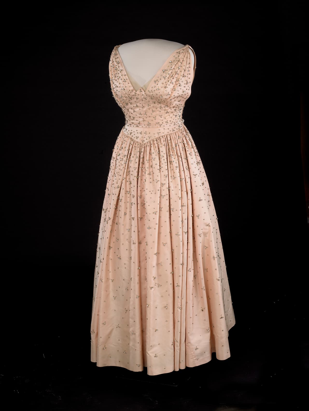 El traje rosa de corte a la cintura tipo 'New Look' como era tradicional de la época fue creado por 
<b>Nettie Rosenstein</b> quien creó a juego también los zapatos y el pequeño clutch. En 1957, la primera dama lo volvería a usar para la cena de estado ofrecida a la embajada británica.