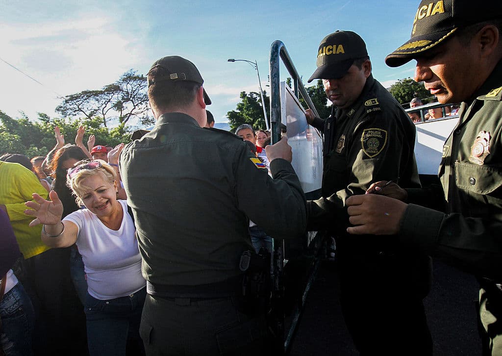 Officials from the Colombian police (right) and Venezuelan (left) raise the fence to open the border while Venezuelans cross the Simón Bolívar bridge from San Antonio del Táchira, Venezuela, to Cúcuta, Colombia, on July 10, 2016. It was the The first time that women dressed in white led the advance towards Colombia, despite the policy of "closed doors". Photo: SCHNEYDER MENDOZA / AFP / Getty Images.