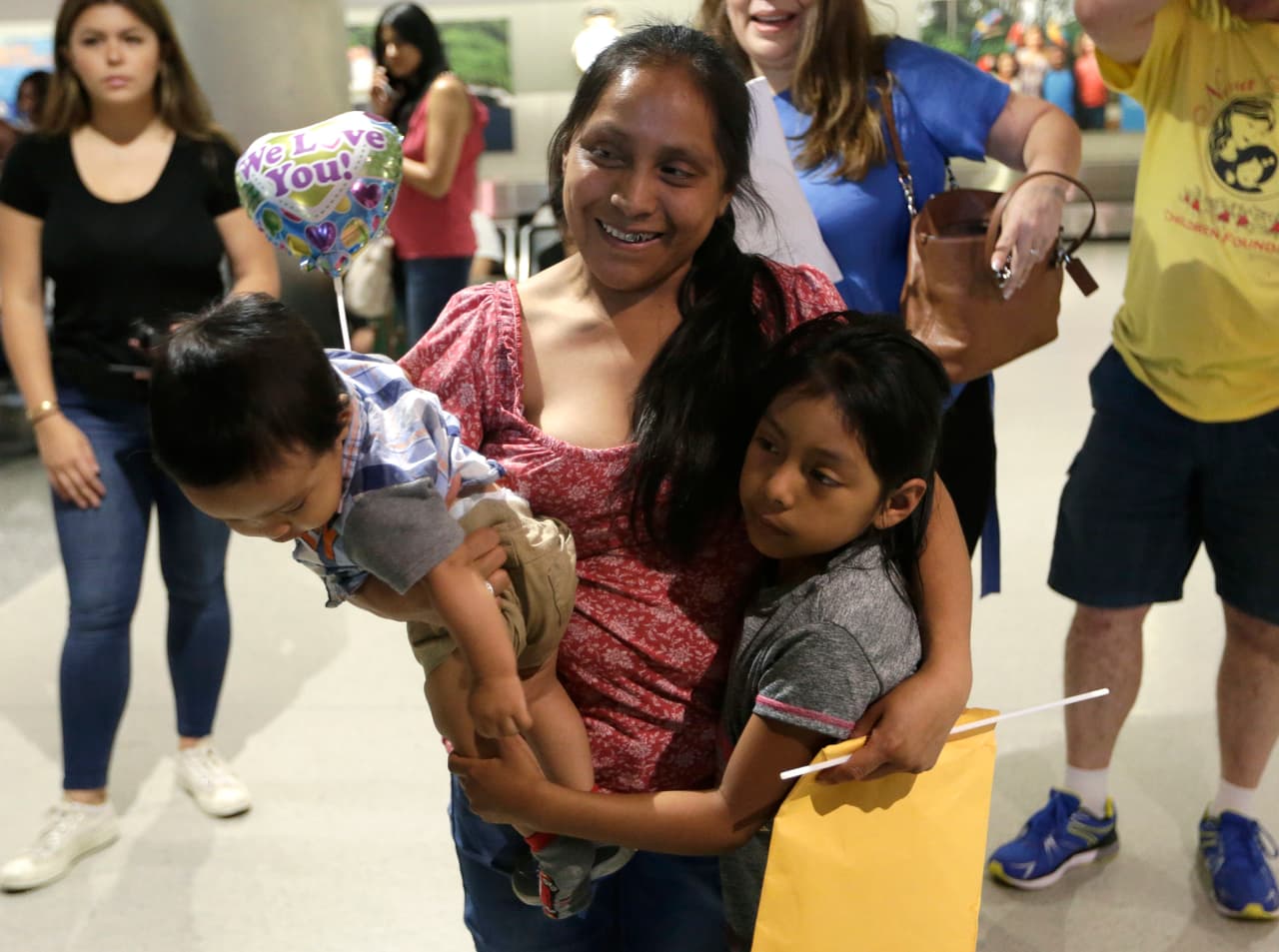 <b>Buena Ventura Martín Godínez</b> (centro), lleva a su hijo Pedro en brazos mientras abraza a su hija Janne (derecha) tras semanas separadas, en el aeropuerto internacional de Miami. Este reencuentro ocurrió el 1 de julio.