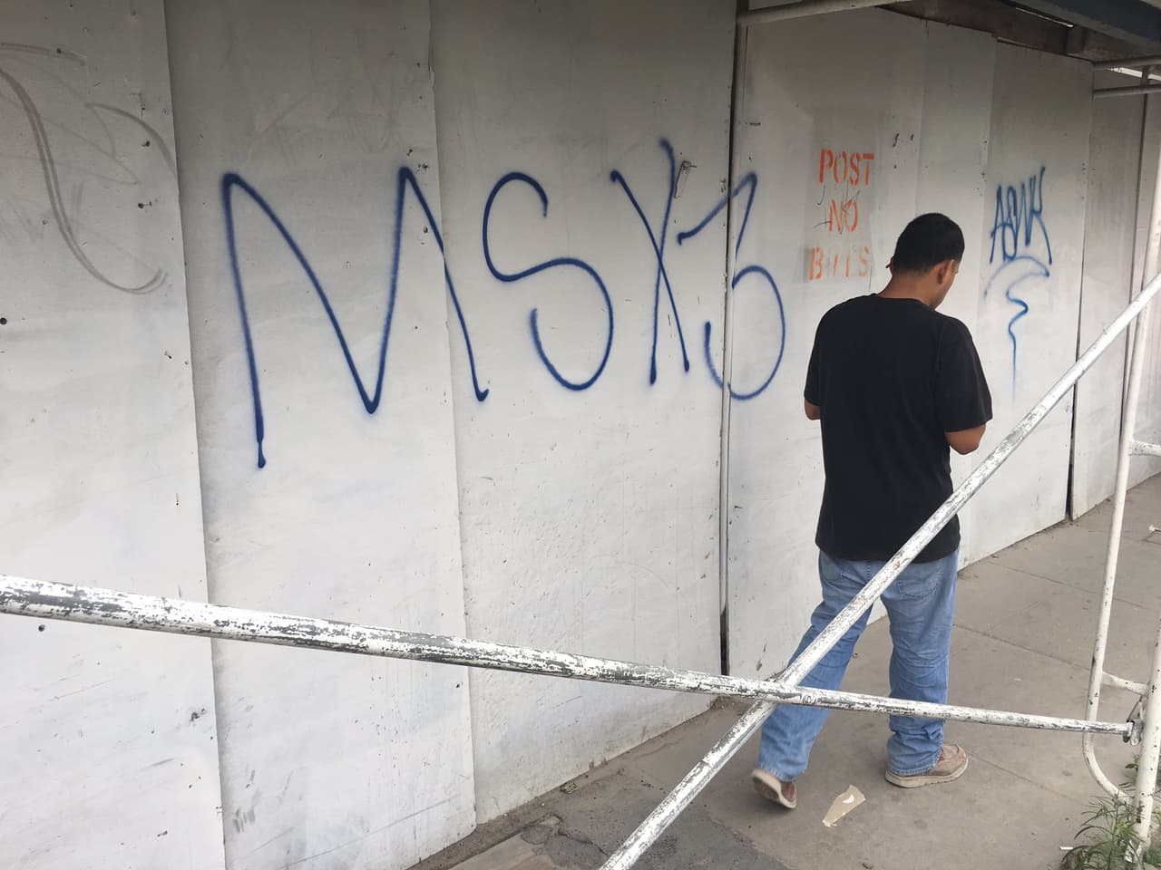 Un hombre camina frente a una construcción cerca del parque Lafayette marcada por la pandilla Mara Salvatrucha.