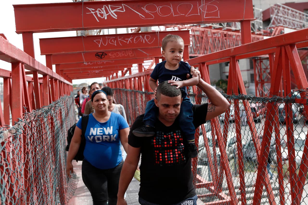 <b>Ciudad Juárez, Chihuahua. Alrededor de 4,000 personas en la lista para solicitar asilo.</b> En este punto fronterizo lista de espera comenzó en octubre de 2018, cuando muchos ciudadanos cubanos comenzaron a dormir en la estrecha acera del internacional entre esta ciudad y El Paso, Texas. Los solicitantes de asilo fueron marcados con números escritos en tinta negra en sus brazos para determinar su posición en la fila. En la fotografía, migrantes cubanos escoltados por autoridades mexicanas cruzan el puente internacional Paso del Norte, entre Ciudad Juárez y El Paso.