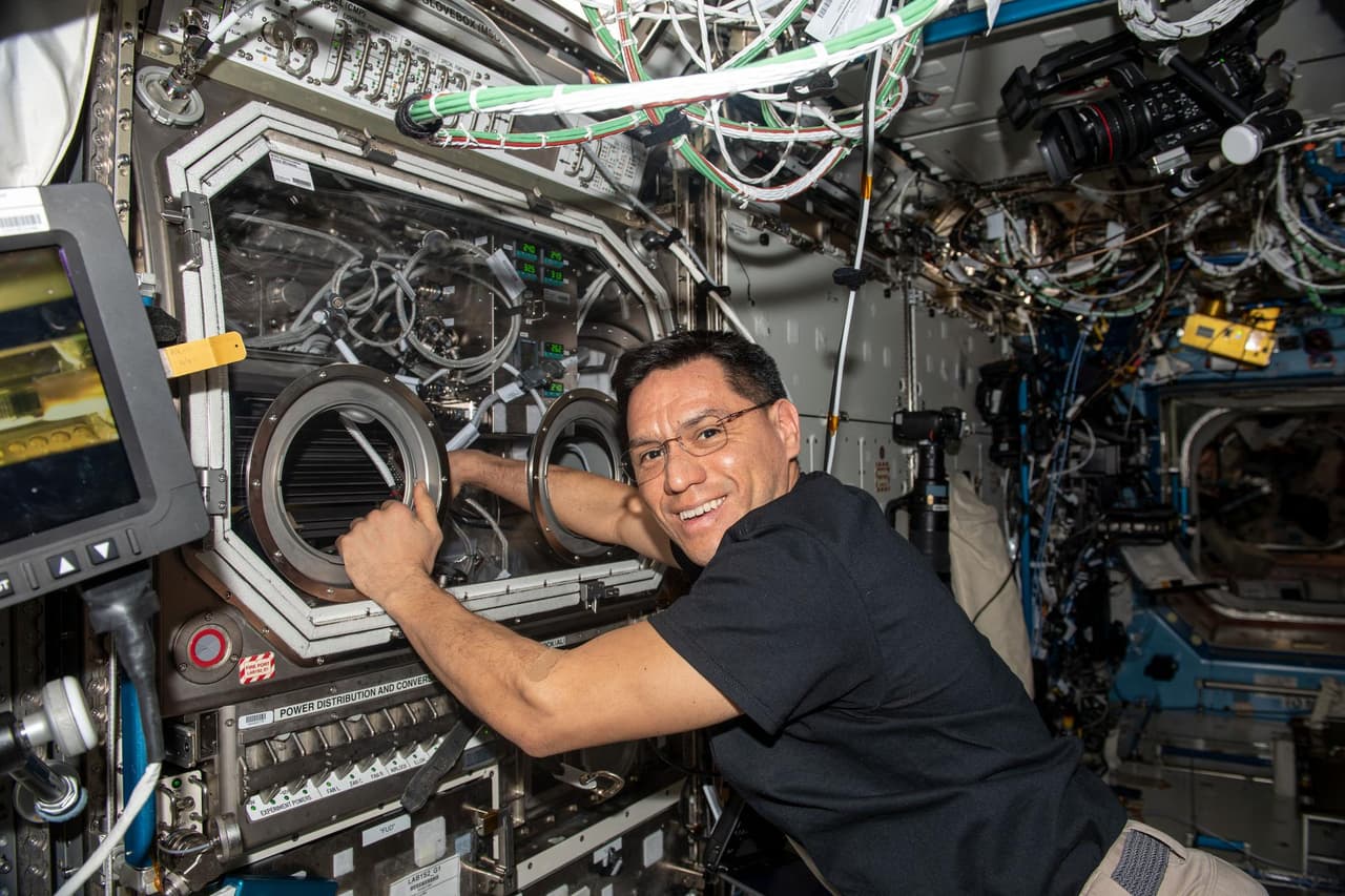 <h3 class="cms-H3-H3">Prueba de materiales para que no queden porosos: </h3>
<br>En esta foto, Frank Rubio intercambia muestras dentro de la guantera científica de microgravedad que ayuda a probar que los materiales mantengan su resistencia. La 
<i>NASA </i>indicó que en la Tierra, las burbujas que se forman en los materiales fundidos suben a la superficie y explotan antes de que el material se solidifique. En microgravedad, las burbujas pueden quedar atrapadas, dejando poros o pequeños agujeros que pueden reducir la resistencia.