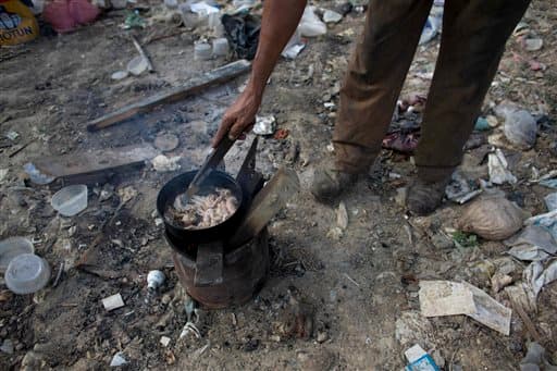 Un hombre cocina piel de pollo que encontró en un basurero de Puerto Cabello. Cuando la comida importada se estropea en puerto, el ejército intenta librarse de ella con discreción enterrándola en vertederos como este. Los vecinos dijeron que han podido recuperar avena, pipas de girasol y alimento para cerdos tirado por el ejército este año.