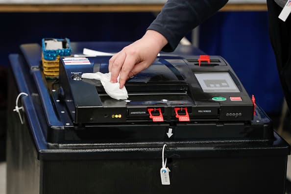 Un trabajador de un centro electoral en Arizona limpia con desinfectante una máquina de lectura de boletas electorales. Muchos de quienes debán atender en los centros de votación no acudieron por temor al coronavirus.