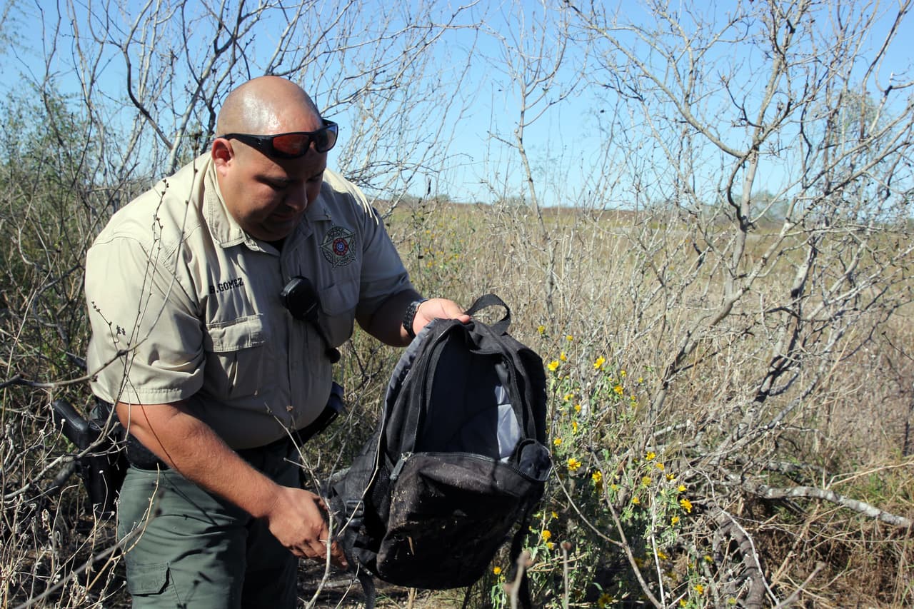Gómez, de 32 años, inspecciona una mochila con algunas pertenencias, previsiblemente de un inmigrante indocumentado que huyó por este monte de clima desértico. La bolsa se encuentra entre los arbustos y ramas con restos de 
<b>comida, ropa y productos de higiene</b>. Los oficiales de la zona creen que el coyote y los migrantes se esconden aquí –ya superado el checkpoint y muy cerca de la carretera estatal–, mientras esperan algún vehículo que los pasa a buscar a toda velocidad.