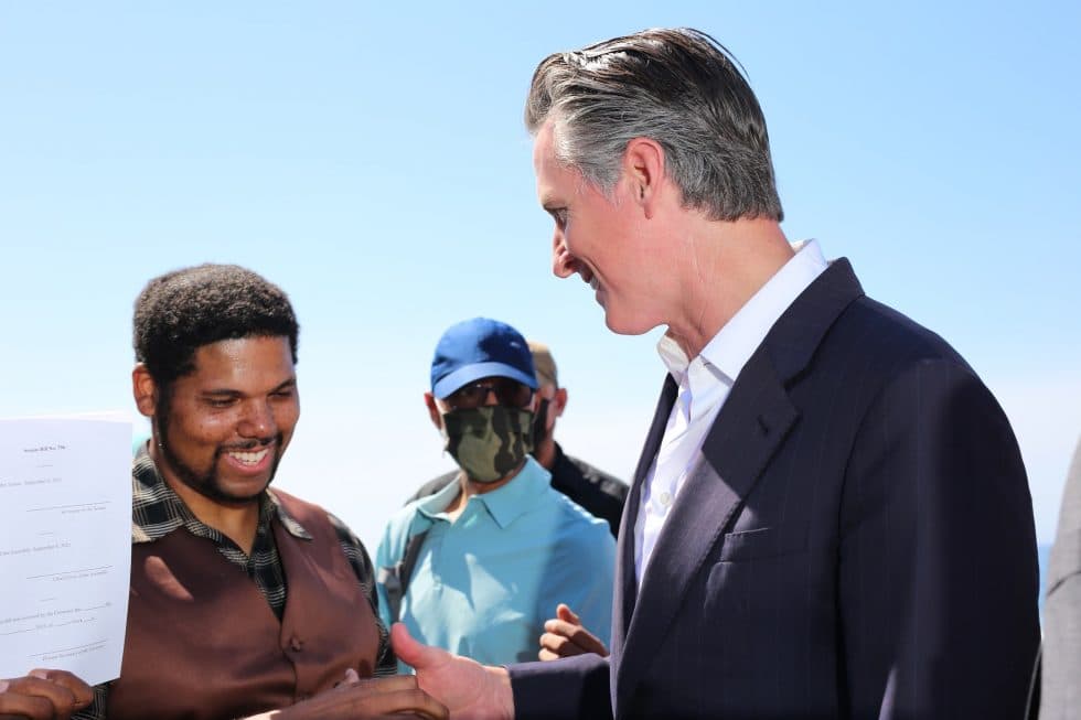 El gobernador firmó la SB 796 del senador Steven Bradford (D-Gardena) hoy en Bruce’s Beach, junto con miembros de la familia Bruce, legisladores y líderes locales. La medida de urgencia, patrocinada por la Junta de Supervisores del Condado de Los Ángeles, autoriza al condado a comenzar de inmediato el proceso de transferencia de parcelas de la propiedad de Manhattan Beach a la familia Bruce.