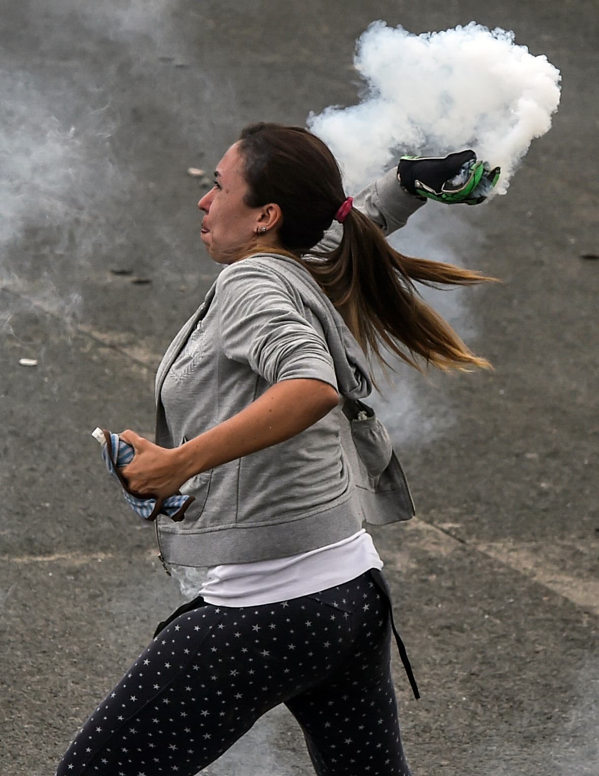 Una mujer lanza con fuerza una bomba lacrimógena a la policía. 20 de abril de 2017.
