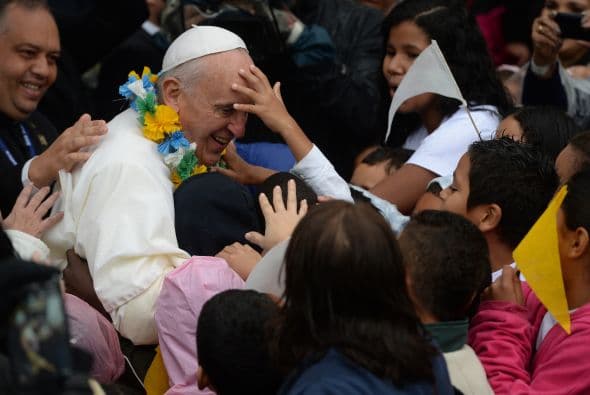 Niños brasileños muy cerca del Papa, que no parece molesto de que la gente quiera tocar su rostro.