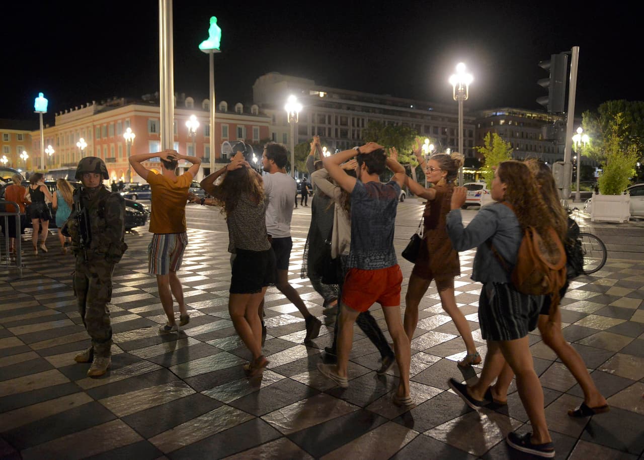 Un grupo de personas abandona el Paseo de los Ingleses con sus manos sobre sus cabezas mientras los soldados resguardan la zona donde el camión embistió a una multitud en Niza. Foto de Jean-Pierre Amet/Reuters.
