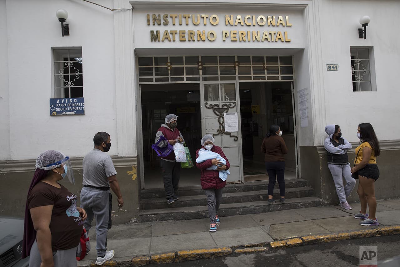 Acompañada de su esposo, Carmen García, de 43 años, 
<b>acuna a su bebé recién nacido en una sala especial para madres con coronavirus</b> del centro médico. 
<br>