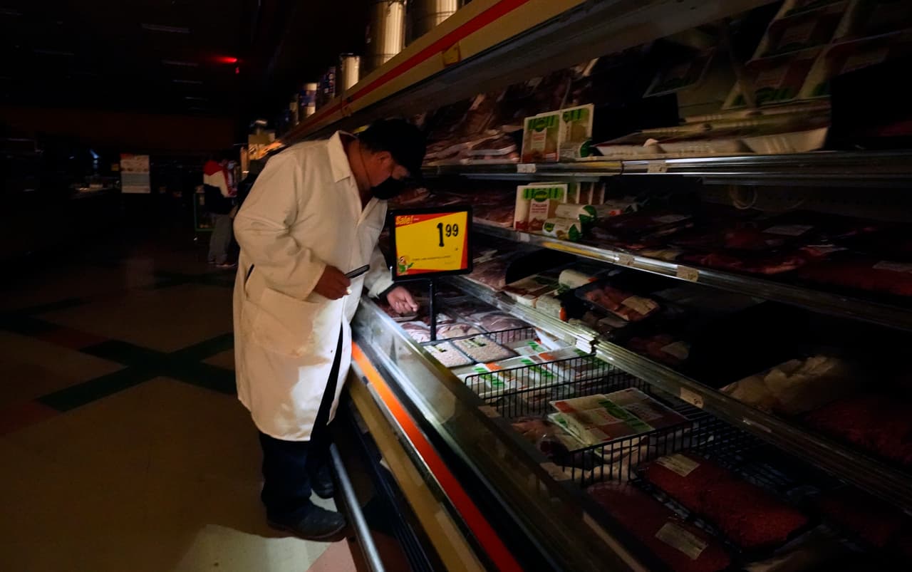 Un empledo de una tienda usa una linterna para ordenar los productos en un establecimiento sin luz en Dallas. Las compañías eléctricas en Texas han implementado apagones controlados para evitar que las redes se sobrecarguen a medida que los residentes necesitan calentar sus hogares.