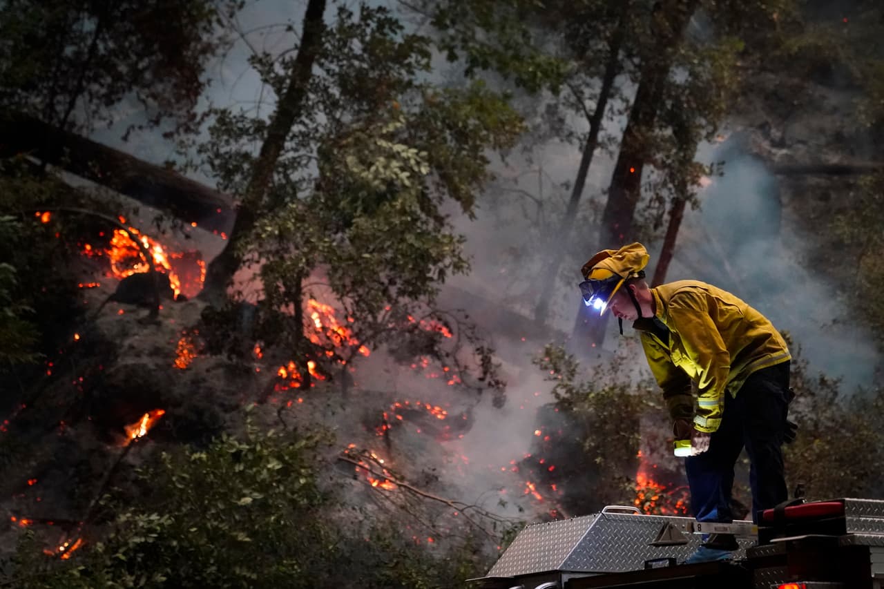 Ben Slaughter, un bombero del Departamento de Bomberos de Boulder Creek, se para sobre un camión de bomberos a lo largo de la autopista 9 
<b>mientras monitorea las llamas del incendio </b>del CZU August Lightning Complex Fire en Boulder Creek, California.
<br>