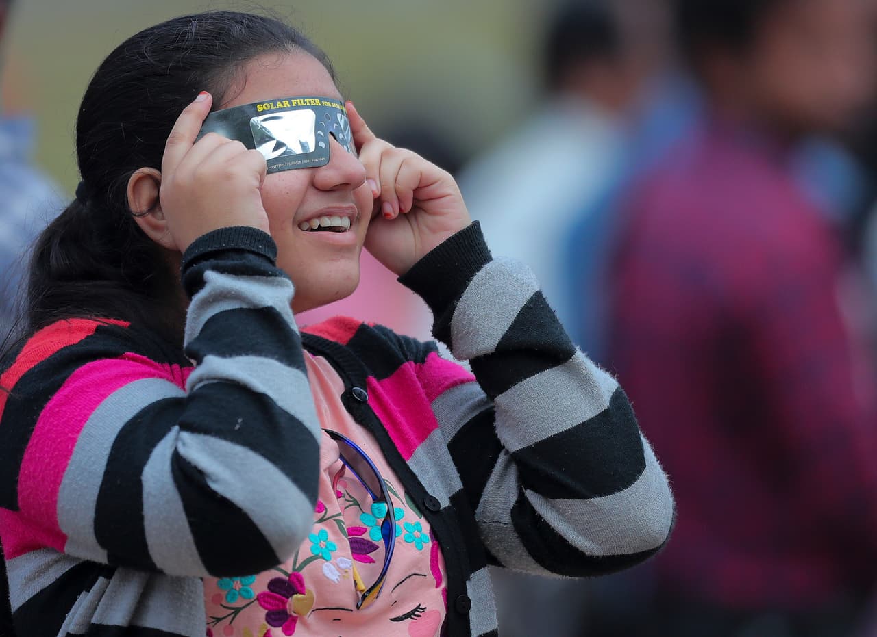 Una niña usa lentes especiales para poner observar el fenómeno en Hyderabad, en el sur de India. A pesar de que la luna cubre parcialmente el Sol, mirar directamente el eclipse puede causar problemas en los ojos.