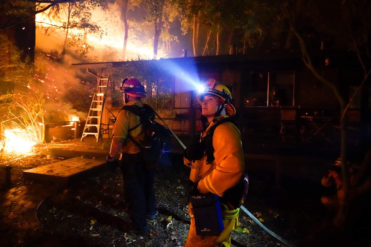 Un bombero monitorea el avance del incendio del CZU August Lightning Complex 
<b>en el patio trasero de una casa</b> en Boulder Creek, California.
<br>