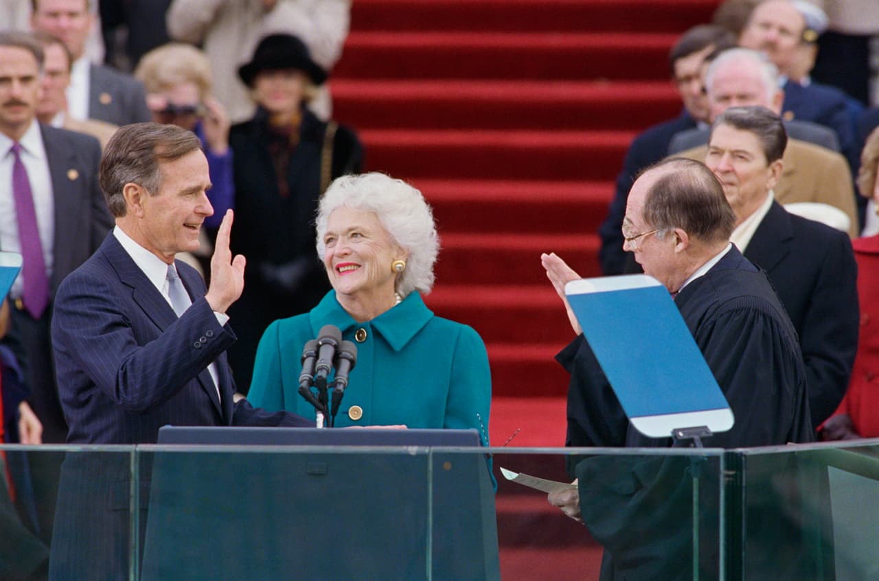 Tras una exitosa campaña en la que Barbara lo acompañó continuamente, Bush vicepresidente de EEUU, fue elegido como el presidente 41 de EEUU. En esta foto del 20 de enero de 1989, se lo ve juramentando mientras su esposa Barbara lo mira amorosamente. De pie en el fondo está Ronald Reagan.