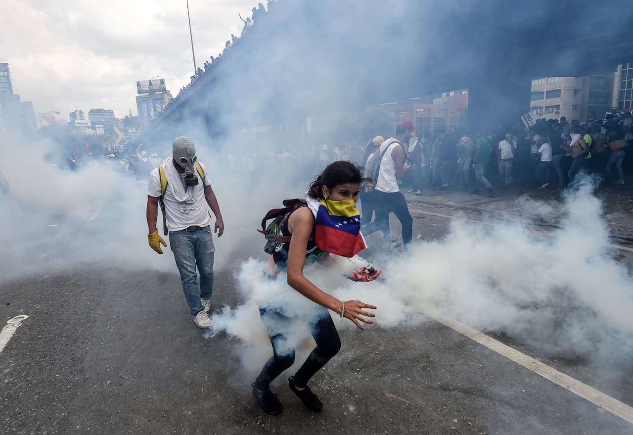 Una manifestante toma con su mano enguantada una bomba lacrimógena. 6 de abril de 2017.