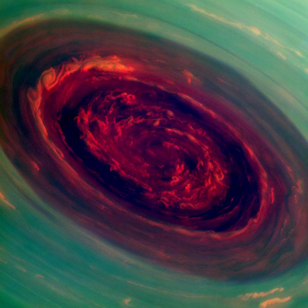 El vórtice giratorio de la tormenta del polo norte de Saturno parece una profunda rosa roja rodeada de follaje verde en esta imagen coloreada. El ojo de la tormenta tiene un diámetro de 1,250 millas y sus nubes se mueven a 330 millas por hora.