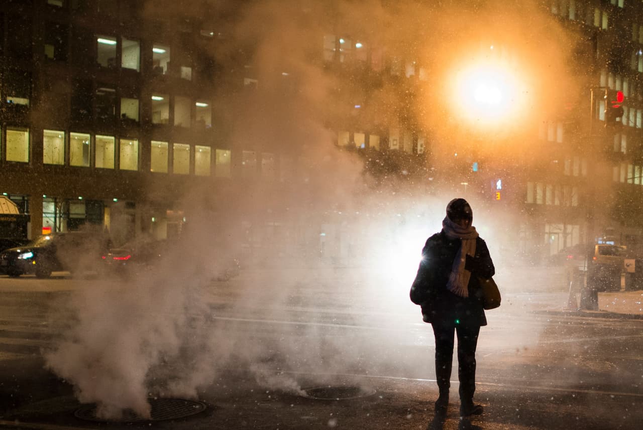 Una mujer camina a través del vapor de una tormenta de nieve mientras cruza la calle en Washington DC.
