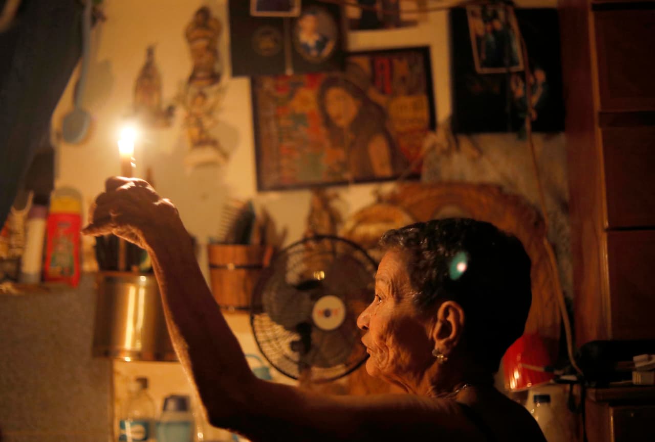 Elizabeth Guzman Espitia, de 72 años, sostiene una vela en su habitación sin ventanas que llama su "pequeña cueva" durante un apagón en el barrio Santa Cruz del Este, en Caracas, el jueves 14 de marzo. Nunca había visto una crisis como esta. Es la primera vez", dijo Espitia. "Me entristece mucho".