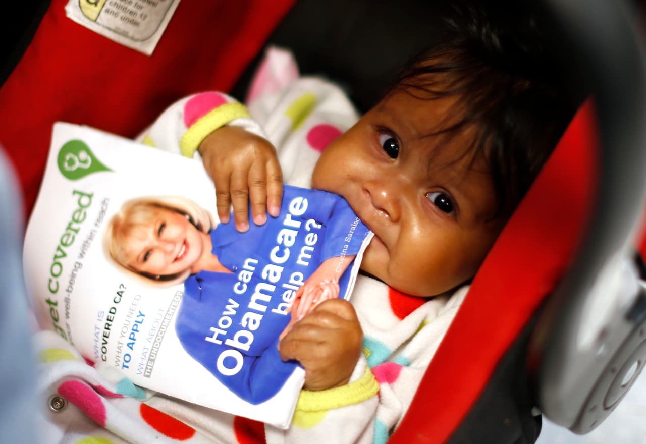 Hazel Garcia, de seis meses, mastica un folleto en un evento de inscripción en seguros de salud en Cudahy, California, el 27 de marzo de 2014. Durante el primer período de inscripción, más de 6 millones de personas se habían inscrito en planes de seguros privados bajo Obamacare.