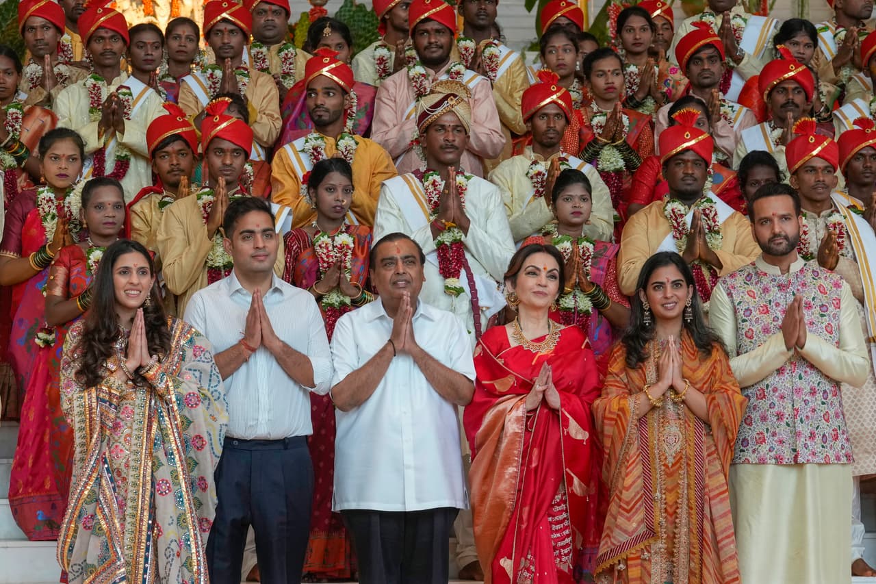 El presidente de Reliance Industries Limited, Mukesh Ambani, tercero desde la izquierda, posa para una fotografía con miembros de su familia y parejas desfavorecidas durante una boda masiva organizada por él como parte de las celebraciones previas a la boda de su hijo menor, Anant Ambani, en Navi Mumbai, India, el martes 2 de julio de 2024.