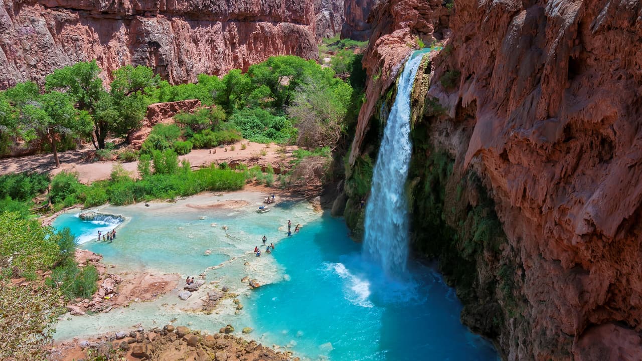 <b>Arizona.</b>
<br>
<br>Havasu Falls, las Cataratas Havasu, están situadas dentro de la Reserva Havasupai, que no forma parte del Parque Nacional del Gran Cañón. Los colores son increíbles: 
<b>el rojo de los paredones de piedra contrastan con el azul del agua. </b>Para ingresar a las cataratas se requiere un permiso y una larga caminata. 
<a href="https://www.visitarizona.com/like-a-local/a-guide-to-visiting-havasu-falls-the-right-way/" target="_blank">El sitio fue cerrado debido a la pandemia y se debe hacer reservas previas.</a> 
<br>
<br>Havasu Falls se encuentra en la reserva Havasupai por lo que deberá comprar un permiso de la tribu Havasupai para acceder al área. Todas las visitas requieren al menos una reserva de una noche.