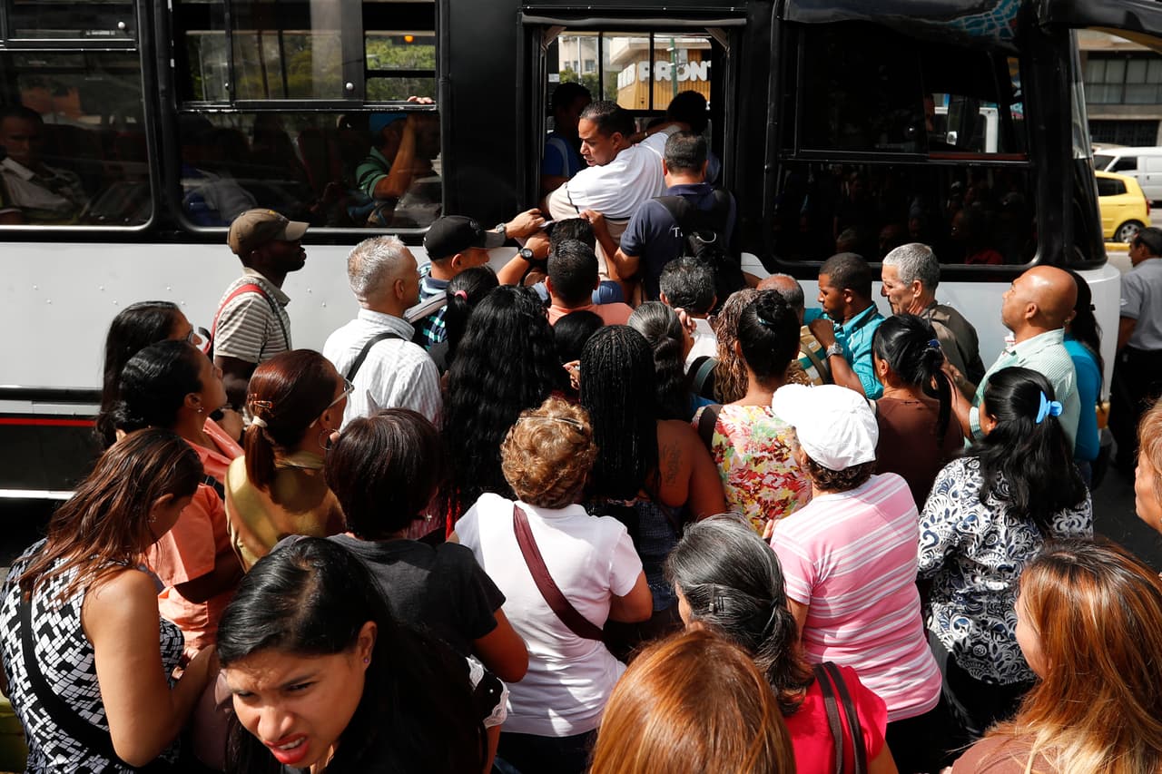 Los empleados públicos de Venezuela fueron llamados a regresar a trabajar el jueves 14 de marzo, aunque el apagón aún mantiene algunas zonas del país sin servicio de agua o telefonía móvil. En la fotografía una multitud intenta alcanzar un puesto en un autobús en Caracas.