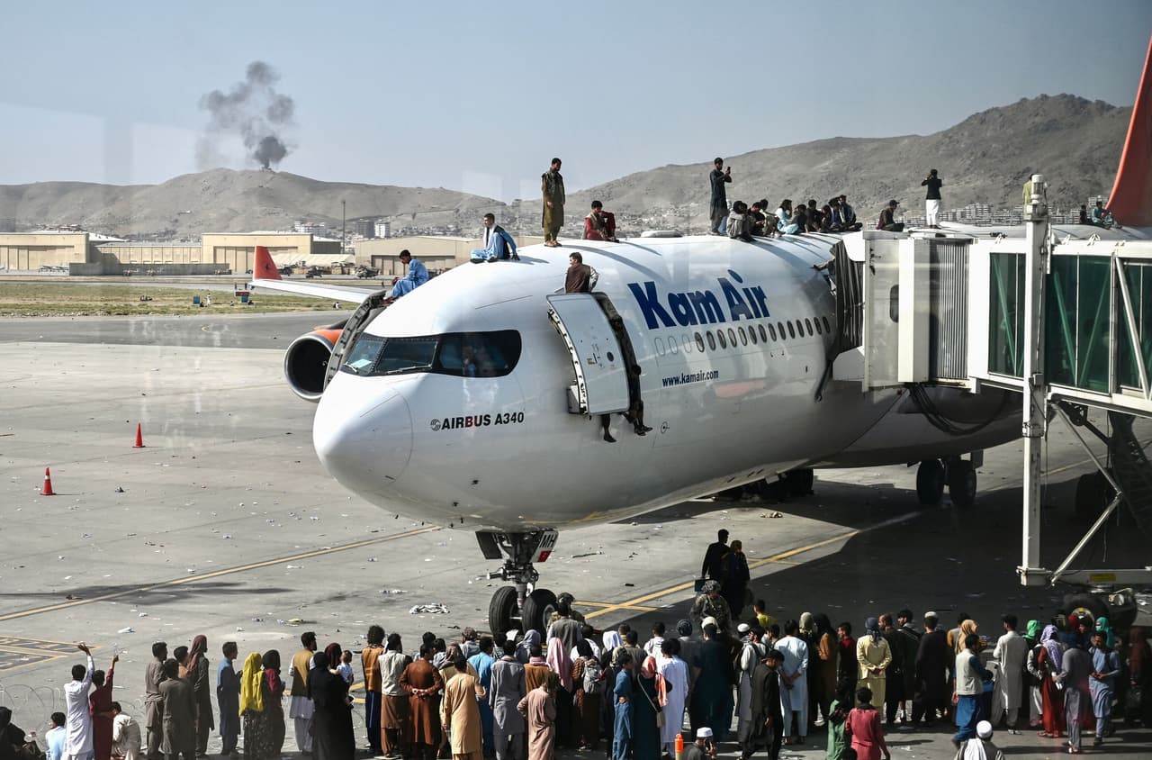 Personas sobre el fuselaje de un avión en el Aeropuerto Internacional Hamid Karzai de Kabul, en la capital afgana. Una marea de gente comenzó a llegar en la noche del domingo al principal aeródromo de la ciudad, muchos de ellos sin ni siquiera documentos de viaje o visado. 
<br>
<br>Las angustiantes escenas se han visto después de que los talibanes entraron en la ciudad culminando su victoria final tras dos décadas de guerra.
<br>