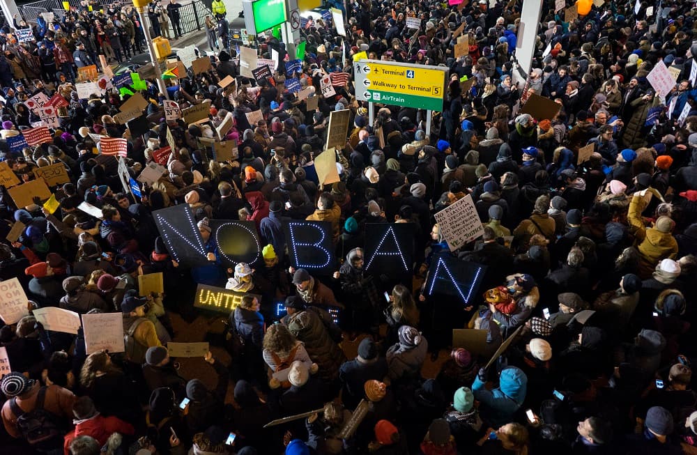 Un grupo sujeta una pancarta con el lema "No al veto" en el aeropuerto de JFK.