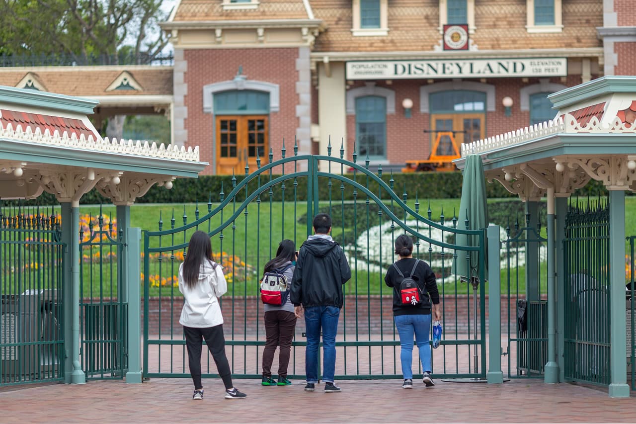 La gente de pie ante las puertas de Disneyland en el primer día del cierre de los parques temáticos Disneyland y Disney California Adventure mientras continúa el temor a la propagación del coronavirus, en Anaheim, California.
