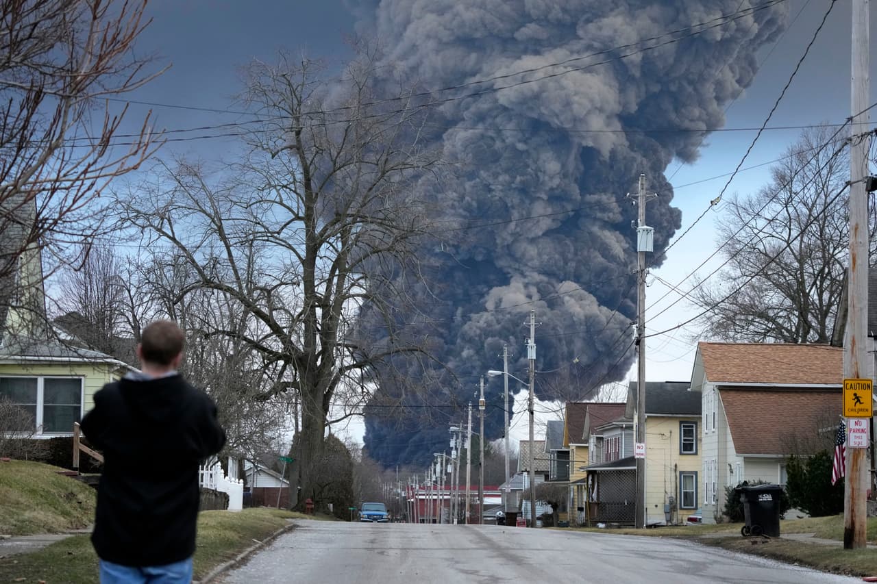 Un hombre toma fotos mientras una columna negra se eleva sobre el este de Palestina, Ohio, como resultado de una detonación controlada de una parte del tren Norfolk Southern descarrilado, el 3 de febrero de 2023.