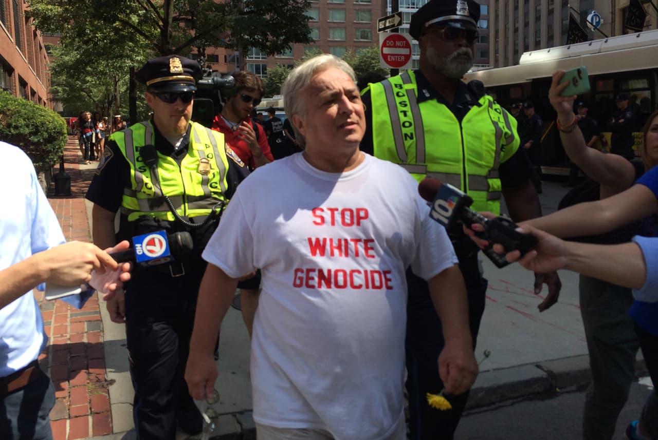 <b>"Detengan el genocidio blanco"</b>. La imagen muestra el momento en que un asistente a la convocatoria de 'Boston Free Speech' es escoltado por miembros de la policía de Boston mientras se retira del Park Square.