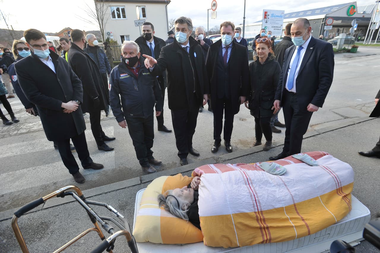 El primer ministro croata, Andrej Plenkovic, (centro) junto a una anciana que fue evacuada a causa del terremoto que dejó también daños considerables a techos y edificios al sureste de la capital.
