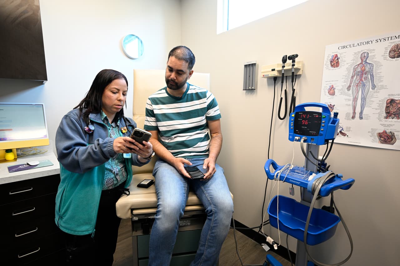 La enfermera Eliza Otero (izq.) habla con Fernando Hermida durante su visita a Pineapple Healthcare en Orlando, Florida, el 28 de mayo de 2024. La clínica atiende a una población LGBTQ+, especialmente a latinos que viven con VIH.