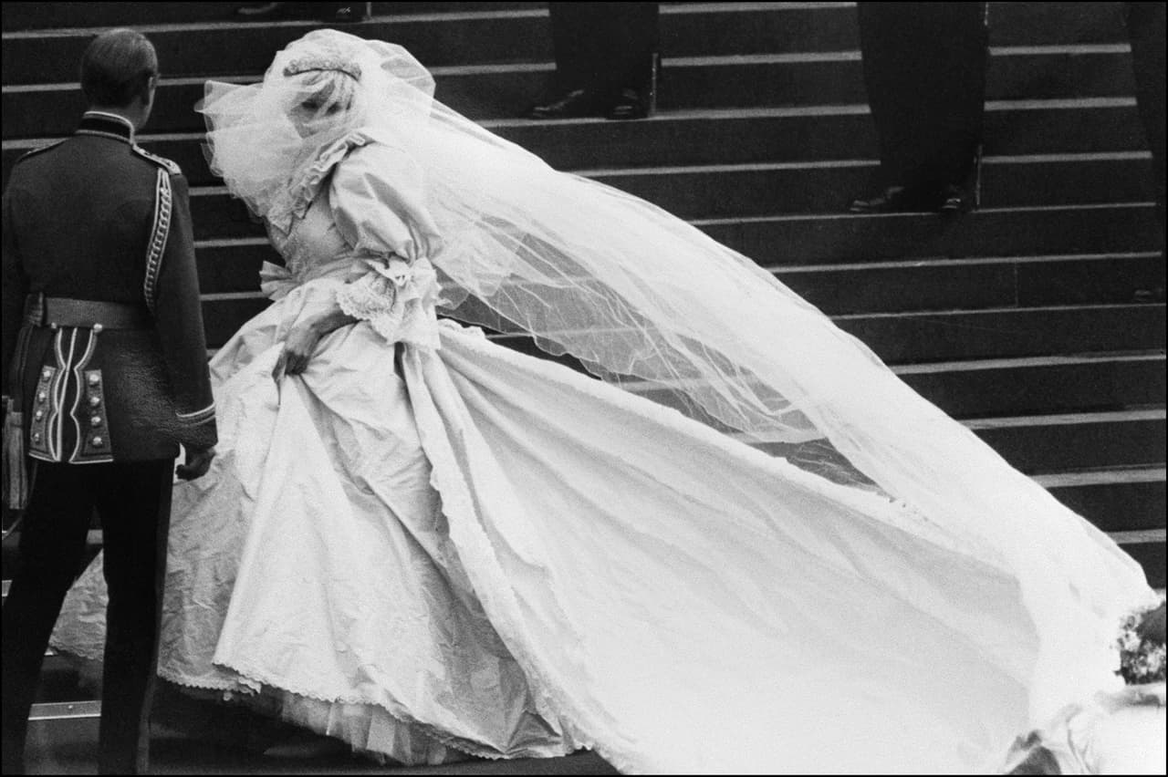Esta escena de ese 29 de julio de 1981 captura la esencia del vestido creado por David Emanuel para la Princesa de Gales. Con una cola de 7 metros de larga, y con más de 10,000 perlas incrustadas a mano, este vestido de ostentosas mangas y mucho volumen sin duda ha sido uno de los más emblemáticos de la historia.