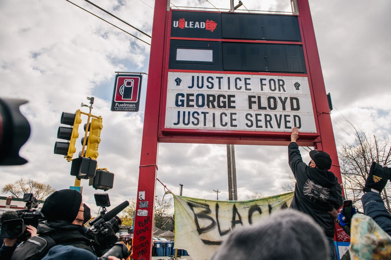 Personas modifican un letrero para poner la leyenda "Justicia para George Floyd. Se ha hecho Justicia" en el mismo lugar donde el afroestadounidense George Floyd pasó sus últimos minutos el 25 de mayo de 2020.