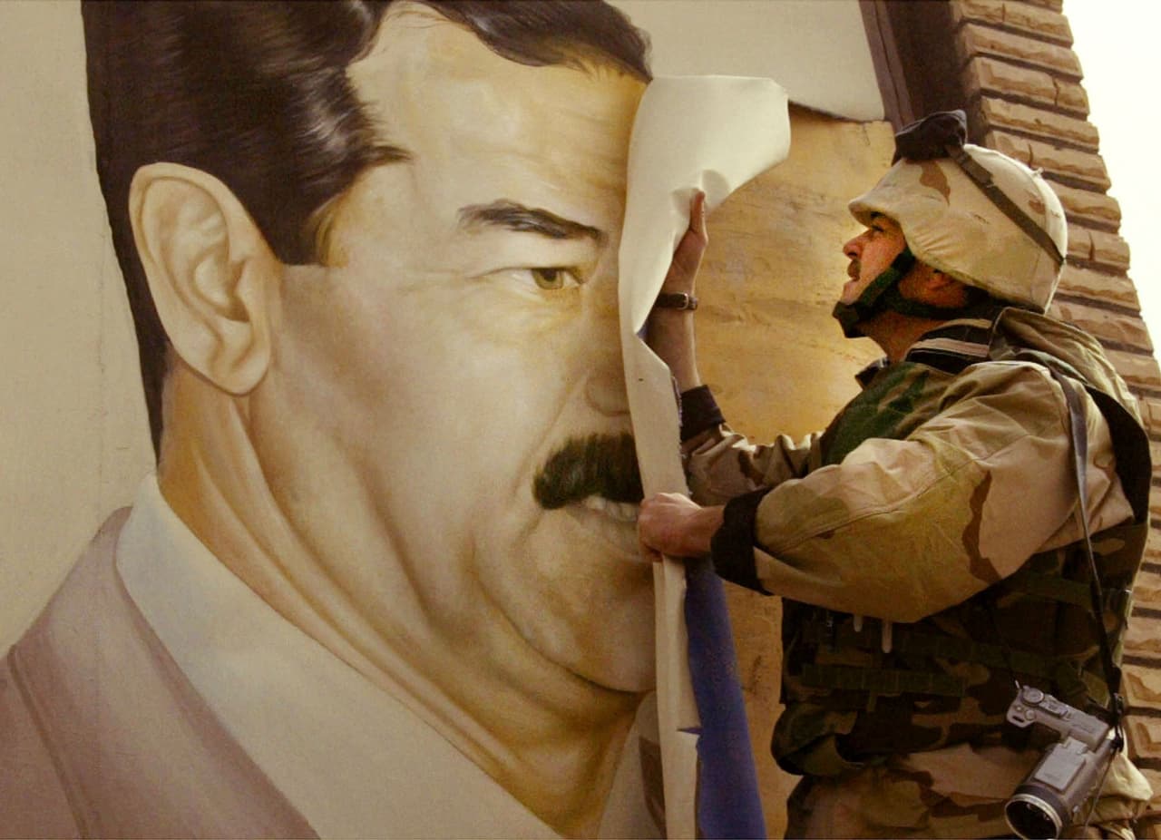Un marine destroza un afiche del todavía presidente de Irak Saddam Hussein en el primer día de la entrada de las tropas estadounidenses al país árabe que acabaría con el derrocamiento del líder iraquí.