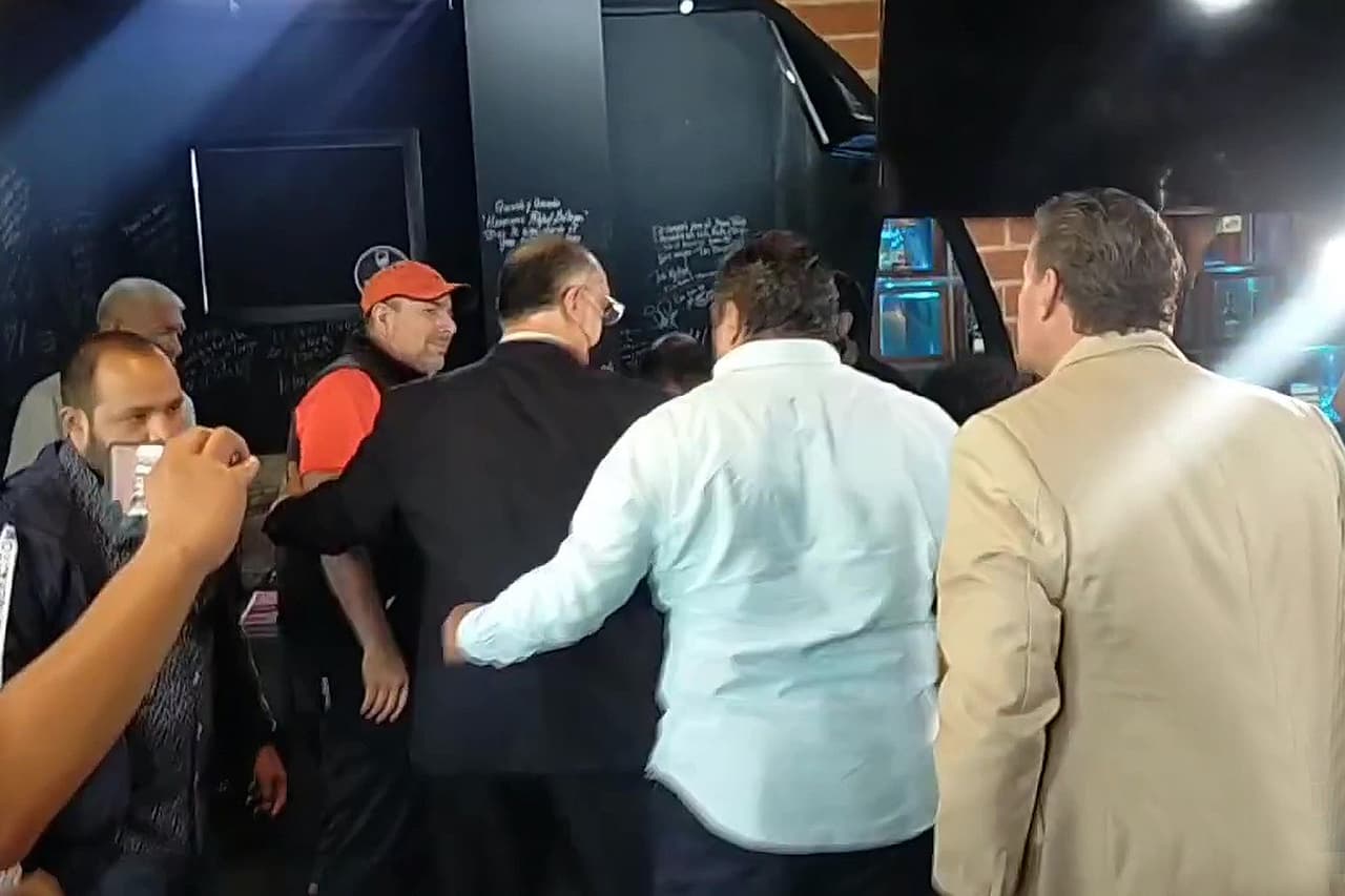 Adame reaccionó cargando una ofensiva a puños, pero al tropezarce con una silla, este terminó de espaldas en el piso tirando patadas.