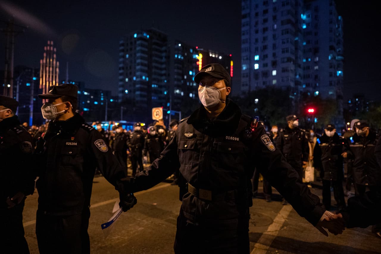 La policía formó un cordón durante una protesta contra las estrictas medidas contra el covid en en Pekín, China. Los manifestantes salieron a las calles en varias ciudades chinas después de que un incendio mortal en un apartamento en la provincia de Xinjiang provocara una protesta nacional, ya que muchos culparon a las severas restricciones de las muertes.