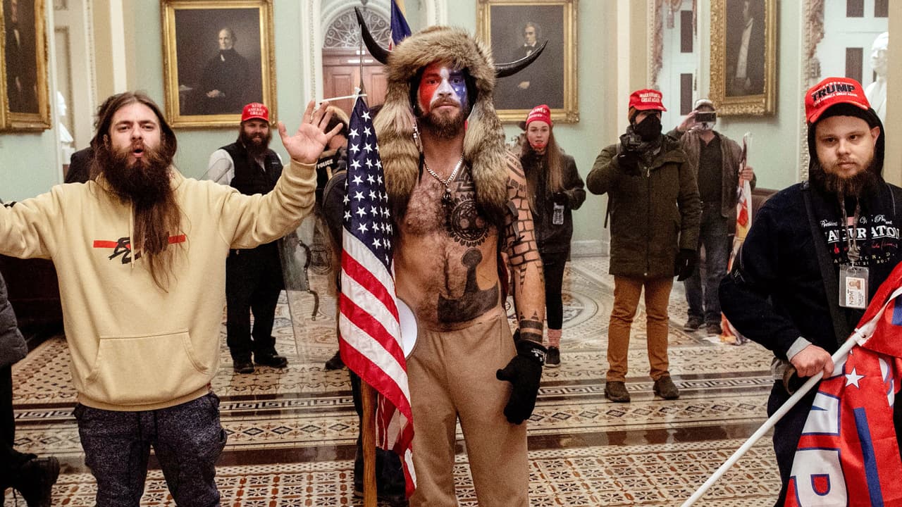 Jake Angeli es el hombre que irrumpió en el Capitolio utilizando una capa con cuernos y con la cara pintada. Gracias a varias fotografías que se tomaron del momento, en las redes sociales lograron identificarlo y se descubrió que él también ha formado parte de otras protestas en Arizona.